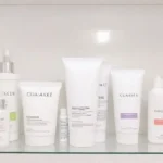 Produtos de cuidados com a pele organizados em uma prateleira iluminada.