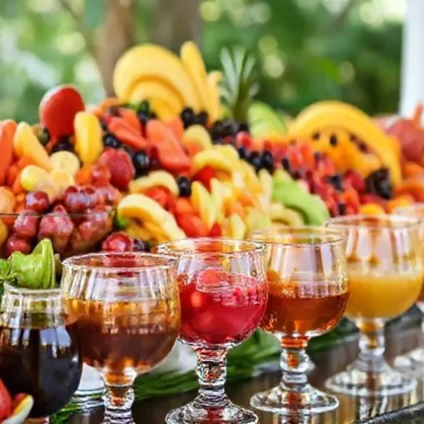 Um buffet de saladas de frutas com caldas variadas em frascos elegantes.