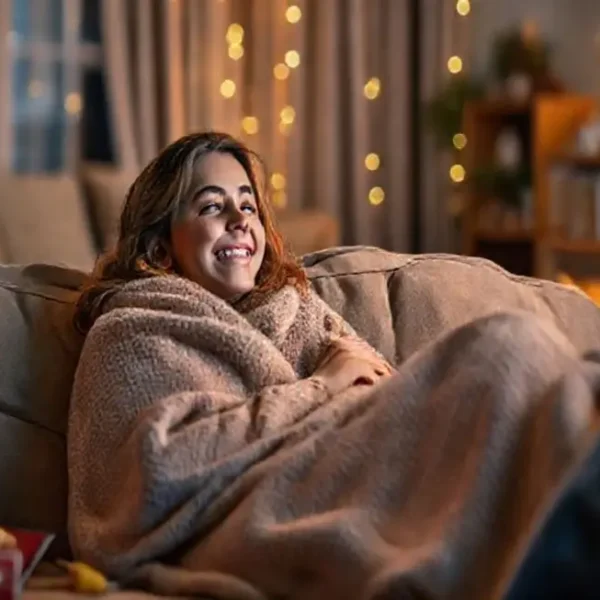 Uma mulher feliz assistindo a um filme em um sofá aconchegante.
