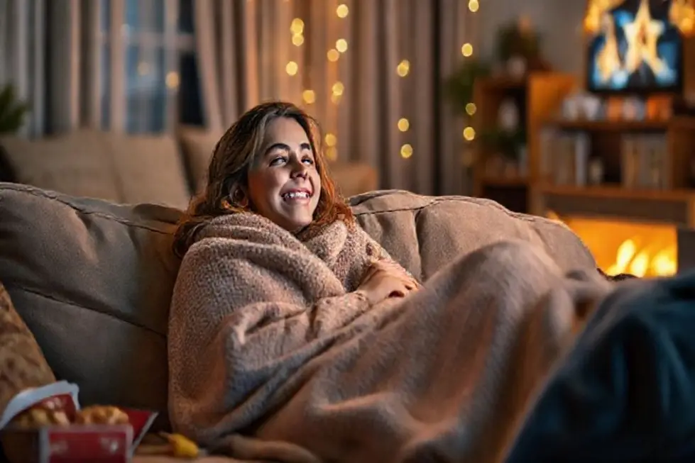 Uma mulher feliz assistindo a um filme em um sofá aconchegante.
