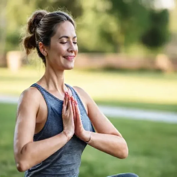 Mulher fazendo yoga em um ambiente natural, representando bem-estar e autocuidado.