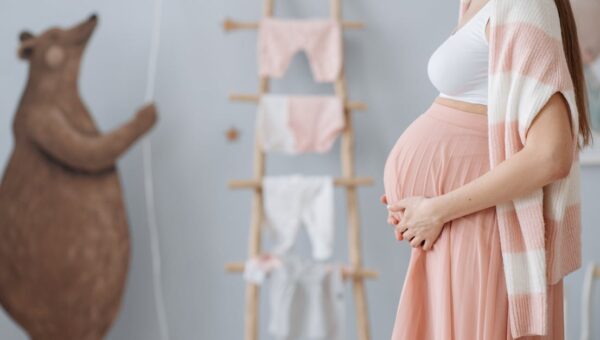 Expectant mother caressing her belly in a cozy nursery room setting, symbolizing love and anticipation.