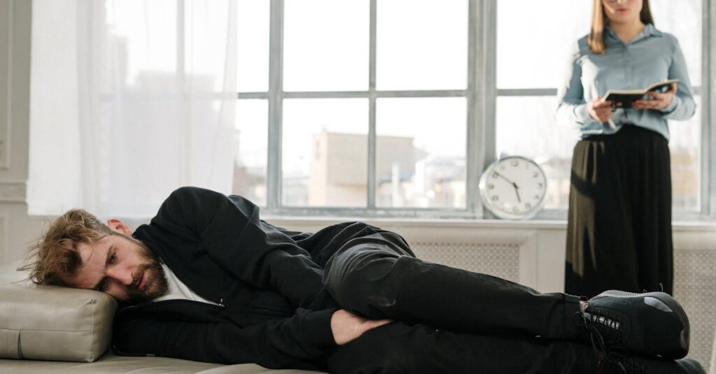 Psychological therapy session with a male patient lying on a couch and a female therapist taking notes.