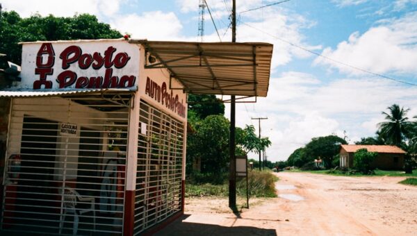 Weathered rural gas station in tropical countryside under a sunny sky.