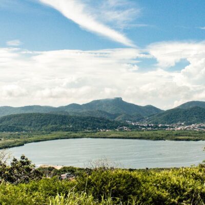 Breathtaking view of Rio de Janeiro's lush hills and serene lake under a vibrant summer sky.