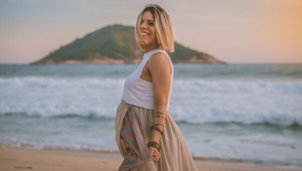 Expecting mother enjoying a serene walk on the beach at sunrise.