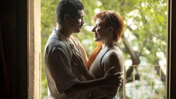 A loving couple sharing a tender moment by a doorway with natural light flowing in. Captured in Buenos Aires.