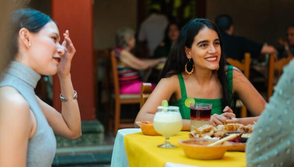 Group of friends enjoying food and drinks at a Mexican restaurant, capturing a lively and festive atmosphere outdoors.