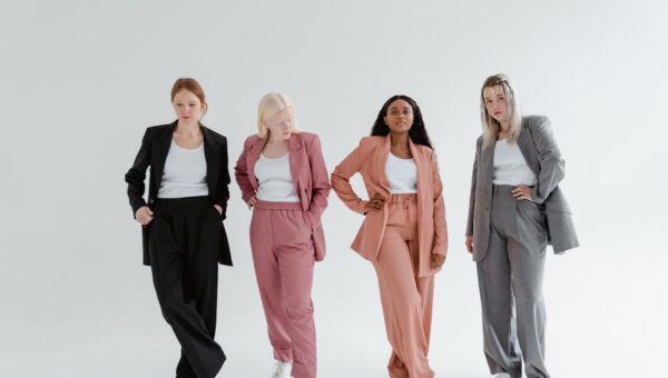 Four women posing confidently in colorful business suits against a white studio background.