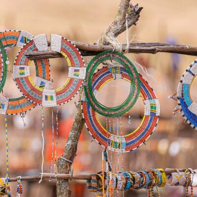 Vibrant Maasai beaded jewelry displayed on wooden racks in Ngorongoro, Tanzania.
