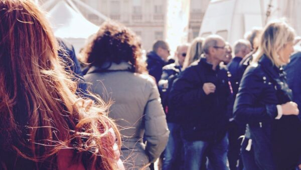 A lively group of people gathers in an outdoor setting during daytime.