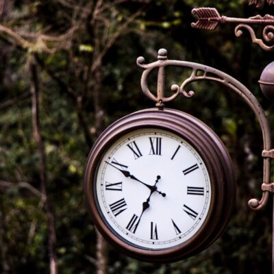 An ornate vintage street clock set against a lush forest background in Vila Suica, Brazil.
