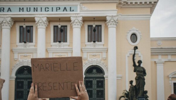 Crowd holding a sign 'MARIELLE PRESENTE' at Rio's city hall.