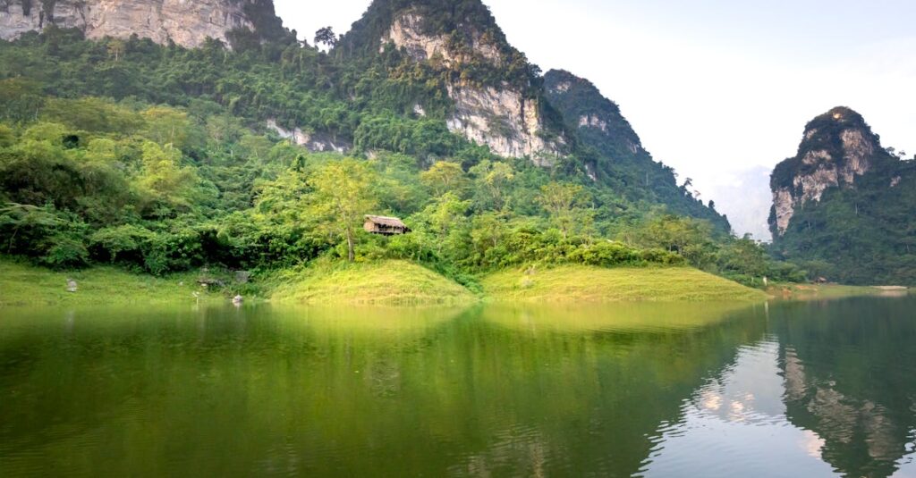 Amazing landscape of calm Na Hang lake surrounded by huge rocky mountains covered with green trees on sunny day in Tuyen Quang province