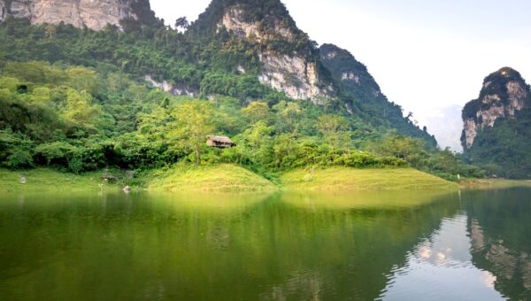 Amazing landscape of calm Na Hang lake surrounded by huge rocky mountains covered with green trees on sunny day in Tuyen Quang province