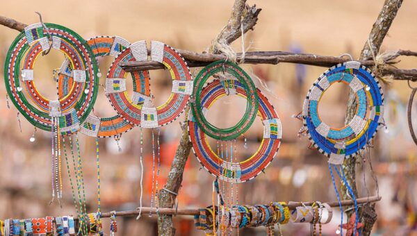 Vibrant Maasai beaded jewelry displayed on wooden racks in Ngorongoro, Tanzania.