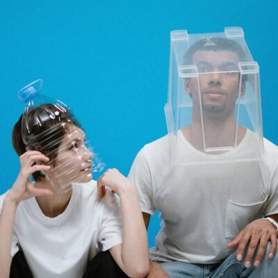 Four people wearing humorous DIY face masks against a blue background, showcasing creativity and humor.