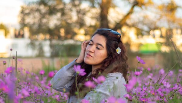Young woman enjoying a moment in a field of vibrant purple cosmos flowers.