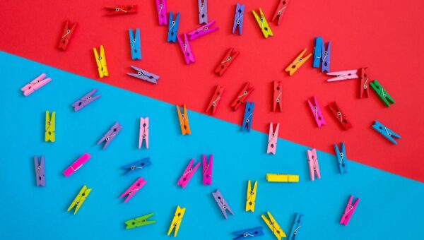 Colorful clothespins scattered on a contrasting red and blue background for a vibrant look.