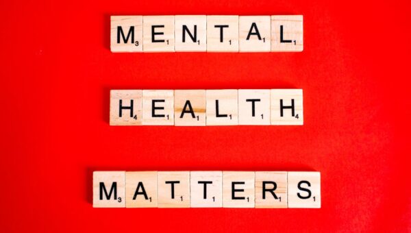 Wooden tiles spelling 'Mental Health Matters' on a vivid red background.