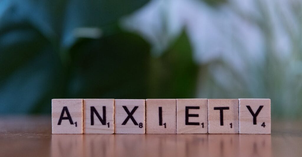 Close-up of wooden blocks spelling ANXIETY on a wooden surface with blurred green background.