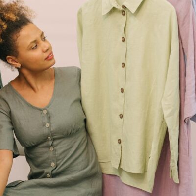 Woman in a boutique admiring beautiful linen clothes on hangers.