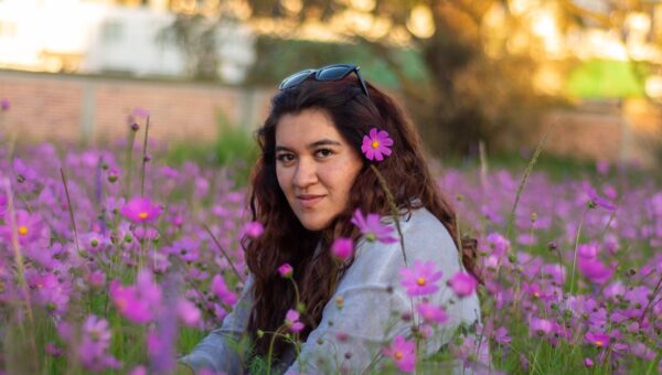 A serene portrait of a woman sitting in a field of pink flowers in Lerma, Mexico, at sunset.