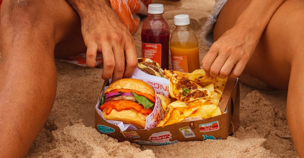 Enjoying a beach picnic with delicious burgers, fries, and drinks. Perfect summer scene.