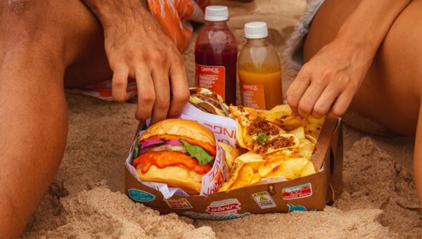 Enjoying a beach picnic with delicious burgers, fries, and drinks. Perfect summer scene.