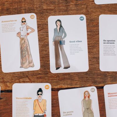 Artistic fashion illustration cards displayed on a wooden table, showcasing style and design.