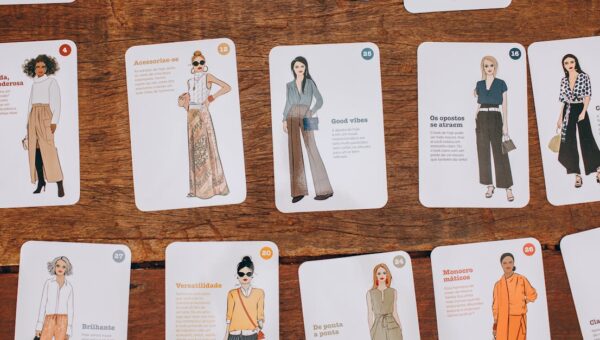 Artistic fashion illustration cards displayed on a wooden table, showcasing style and design.