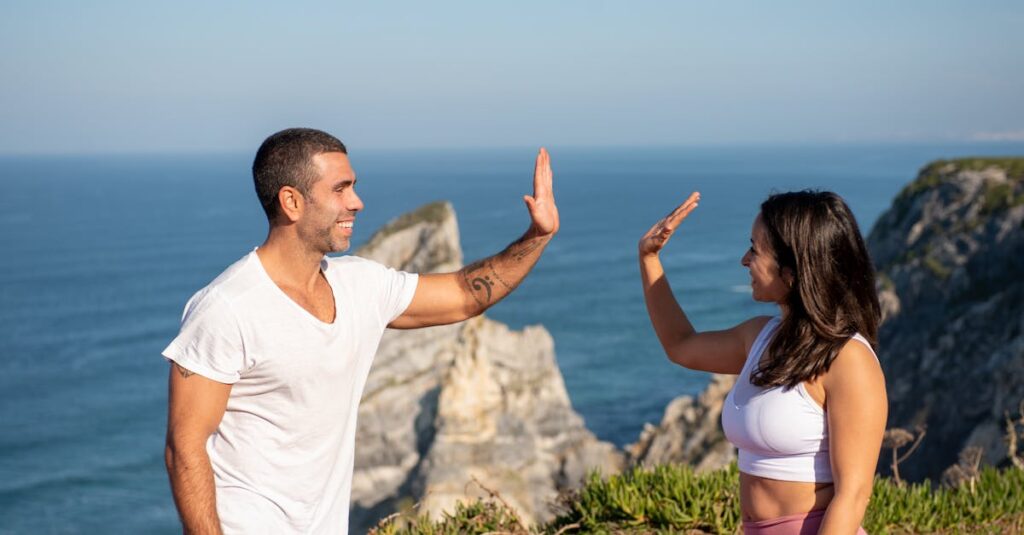 Fit couple in athletic wear high-fiving by the sea on a sunny day in Portugal.