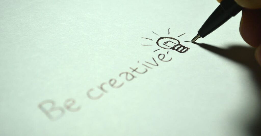 Close-up of handwritten 'Be creative' with a light bulb sketch on paper.