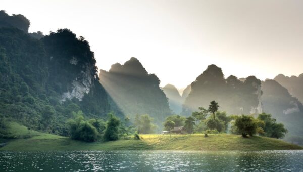 Peaceful scene of sunlit mountains and a tranquil lake in Tuyen Quang, Vietnam.