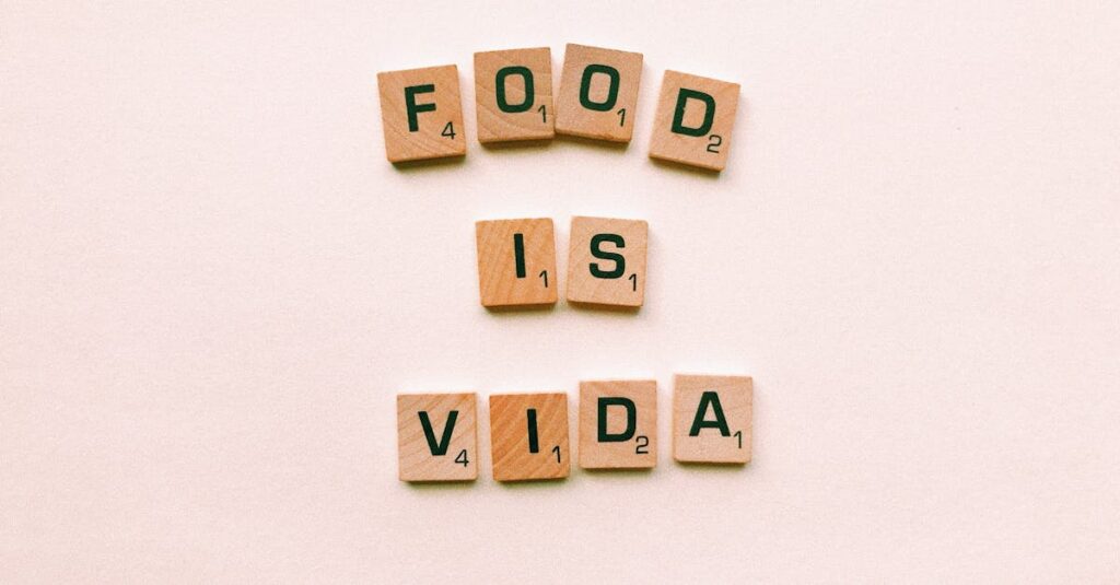 Wooden letter tiles spell 'FOOD IS VIDA' on a soft pink background.