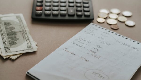 Desk setup showing calculator, cash, coins, and financial notes for budgeting.