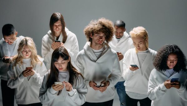 A group of diverse young adults focused on smartphones, symbolizing modern technology and digital connection.