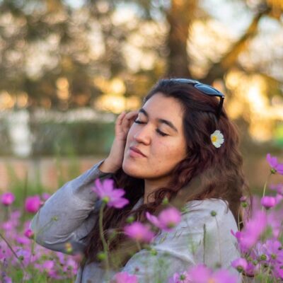 Young woman enjoying a moment in a field of vibrant purple cosmos flowers.