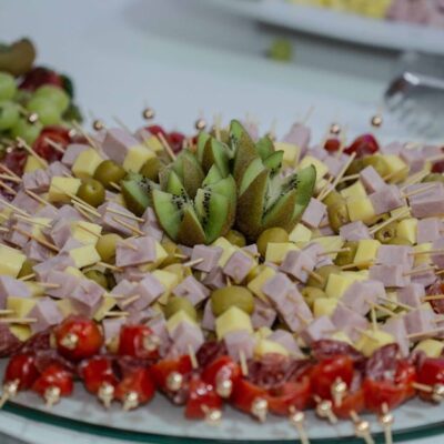 Vibrant platter of fruit and cheese skewers with kiwi, olives, and tomatoes, perfect for snacking.