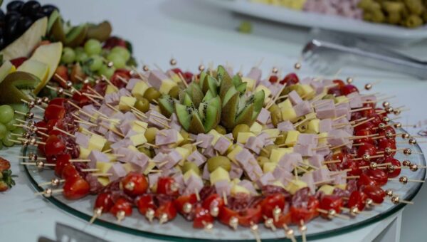 Vibrant platter of fruit and cheese skewers with kiwi, olives, and tomatoes, perfect for snacking.