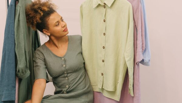 Woman in a boutique admiring beautiful linen clothes on hangers.