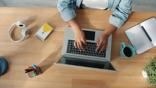 Top-down view of a person working on a laptop at a neat desk with accessories.