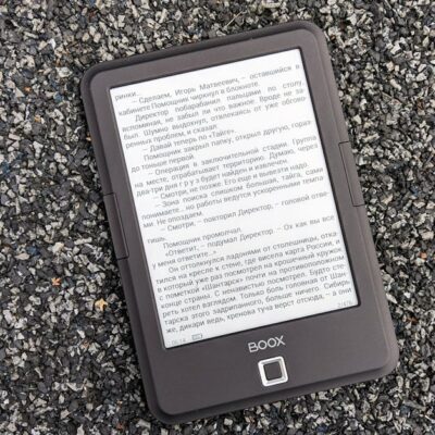 Digital BOOX e-book reader placed on a textured gravel surface, offering a tech contrast.