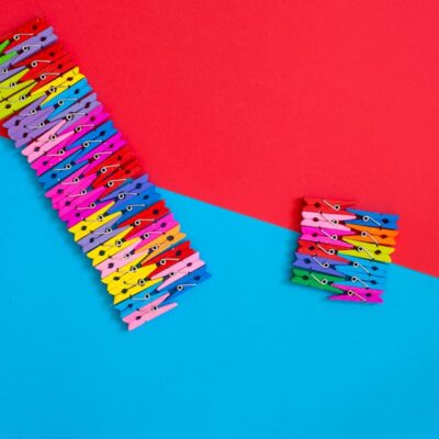 Multicolored clothespins arranged creatively on a red and blue geometric background.