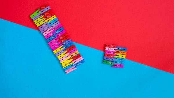 Multicolored clothespins arranged creatively on a red and blue geometric background.