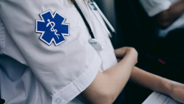 Paramedics in uniform work with medical charts inside an ambulance.