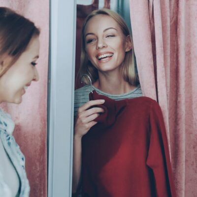 Two women enjoying a shopping experience, smiling in a changing room.