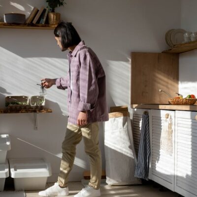 Man in casual wear tending to indoor plants in a sunlit kitchen.