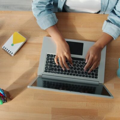 Top-down view of a person working on a laptop at a neat desk with accessories.