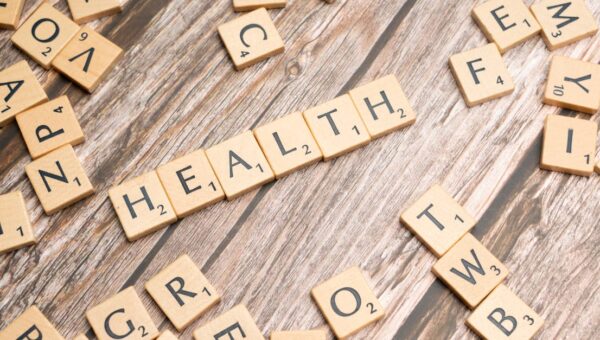 Scrabble tiles spelling 'HEALTH' on wooden surface, symbolizing wellness.